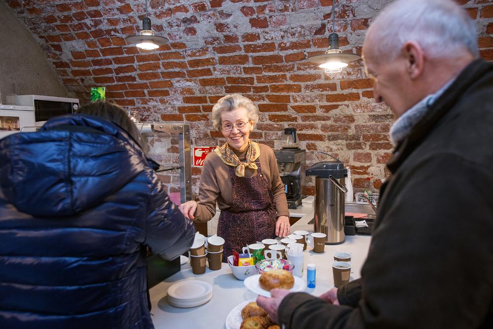Ihmisiä ostamassa kahvia Domcafén iloisesti hymyilevältä myyjältä.