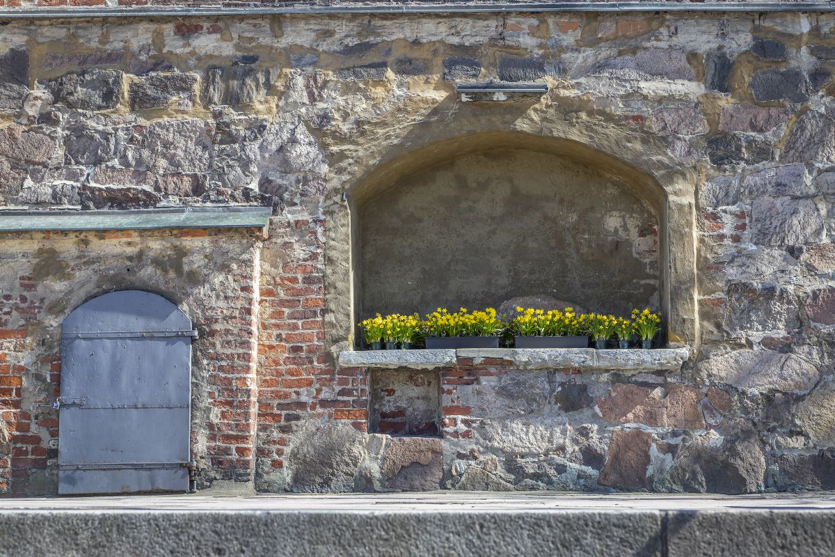 Ulkoalttarin syvennys kirkon kivijalassa, vasemmalla raskaannäköinen ovi