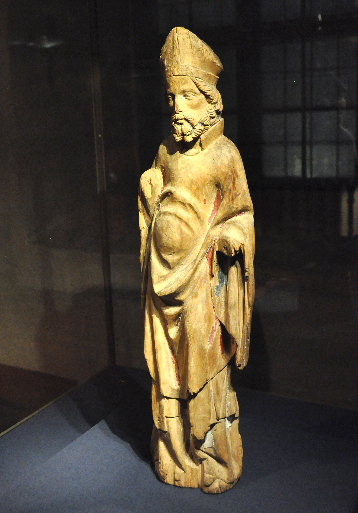 Puinen miestä esittävä patsas, jossa värikkään maalin jäänteitä uurteissa